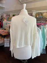 White sweater with star patterns on a mannequin in a store setting.