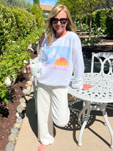 Woman wearing a white sweatshirt with a graphic design outdoors