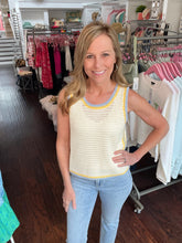 Woman wearing a yellow crochet top and blue jeans in a clothing store.