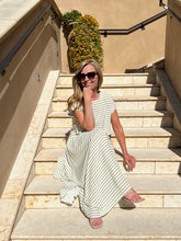 Woman in a striped dress sitting on stone steps outdoors