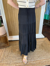 Person wearing a black tiered skirt and white top in a store setting.
