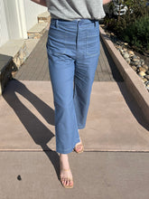 Person wearing blue wide  pants on a concrete surface.