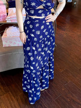 Woman standing in a store wearing a navy seashell print skirt.