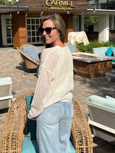Woman wearing a cream sweater standing outdoors in front of a building with 'Carmel Mission Inn' sign.