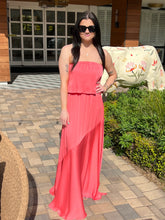 Woman in a coral dress standing outdoors on a patio