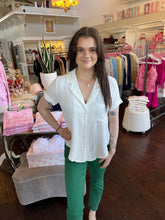 Woman wearing a white short sleeve blouse while standing in a store.