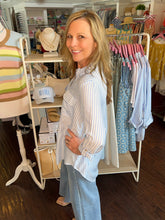 Woman standing in a clothing store with racks of clothes and mannequins in the background.