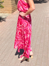 Person wearing a pink floral dress on a paved walkway.
