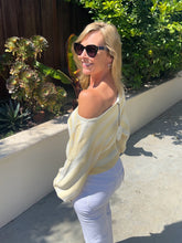 Woman wearing a yellow striped shirt and sunglasses outdoors