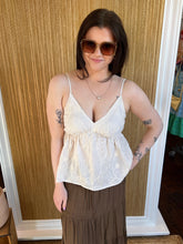 Woman wearing a white lace top and brown skirt indoors.