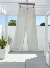 White pant hanging on a pink hanger on a patio.