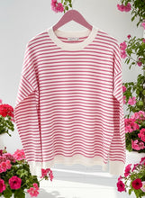 Pink and white striped sweater with white cuffs on a hanger.
