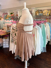 Mannequin wearing a beige dress with ruffle skirt in a store setting.