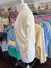 Cream woven sweater on a mannequin side view in a clothing store setting