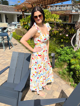 Woman in a colorful dress standing outdoors near a building with 'Carmel' on the sign.