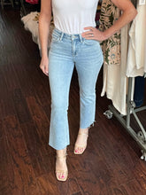 Person wearing light blue jeans and a white top in a store setting.