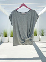 Gray sleeveless tie top on a hanger with a white background and plants.
