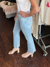 Person wearing light blue jeans and a white top in a clothing store.