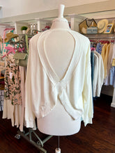 White open back sweatshirt on a mannequin in a clothing store setting