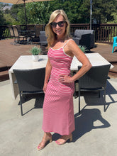 Woman in a red and white striped dress standing on a patio with outdoor furniture.