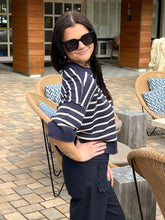 Woman wearing a navy and white striped sweater and sunglasses outdoors.