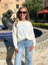 Woman wearing a sweater with fish designs in front of a fountain