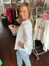 Woman standing in a clothing store with racks of clothes in the background