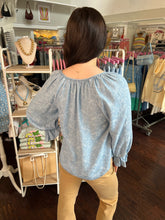 Person wearing a light blue blouse in a store setting