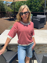 Woman wearing a red and white striped sweater and sunglasses outdoors.