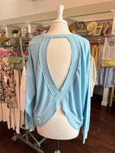 Light blue open back sweatshirt on a mannequin in a clothing store setting