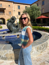 Woman standing by a pool with a sculpture in the background