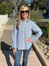 Woman wearing a blue and white striped shirt and sunglasses outdoors.