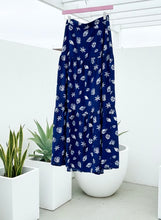 Navy skirt with seashell pattern fabric hanging on a hanger on a patio.