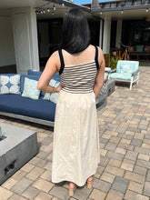 Woman in a striped dress standing on a patio with outdoor furniture and decor.