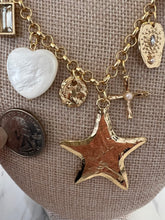 Gold charm bracelet with various charms including a star, heart, and cross, next to a quarter for scale.