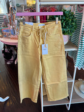 Yellow pants with a tag on a rack in a store setting