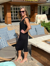 Woman in a black dress standing outdoors near patio furniture with 'Mission Inn' in the background.