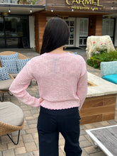 Person wearing a pink sweater and dark pants standing in front of a building with decorative cows.