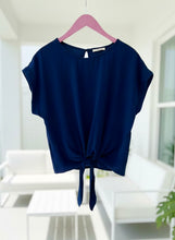 Navy blue top with a tie detail on a pink hanger against a white background
