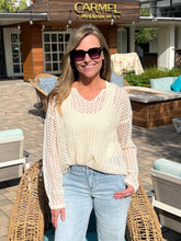 Woman wearing a cream sweater standing outdoors in front of a building with 'Carmel Mission Inn' sign.