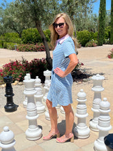Woman in a striped dress standing next to oversized chess pieces in an outdoor setting.