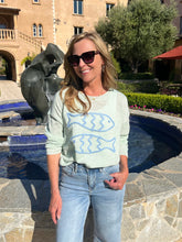 Woman standing by a pool with a sculpture and building in the background
