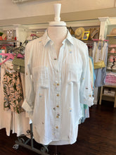 White striped shirt on a mannequin in a store setting with clothing racks and shelves in the background.