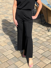 Person wearing black pants and a black top on a paved outdoor floor.