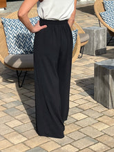 Person wearing black wide-leg pants standing on a patio with outdoor furniture.