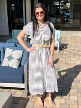 Woman in a striped dress standing outdoors on a patio.