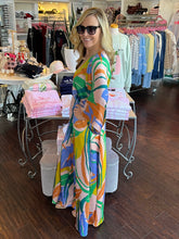 A woman wearing a bold print kimono maxi standing in a store by a display.