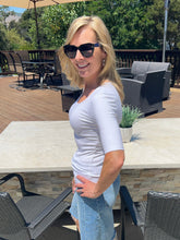 Woman wearing sunglasses and a white shirt outdoors on a patio