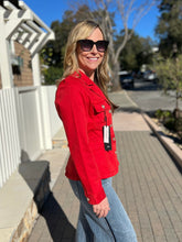 Woman wearing a red peplum jacket and sunglasses outdoors on a sunny day.