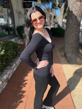 Woman in black long sleeve posing on a sidewalk with trees and buildings in the background